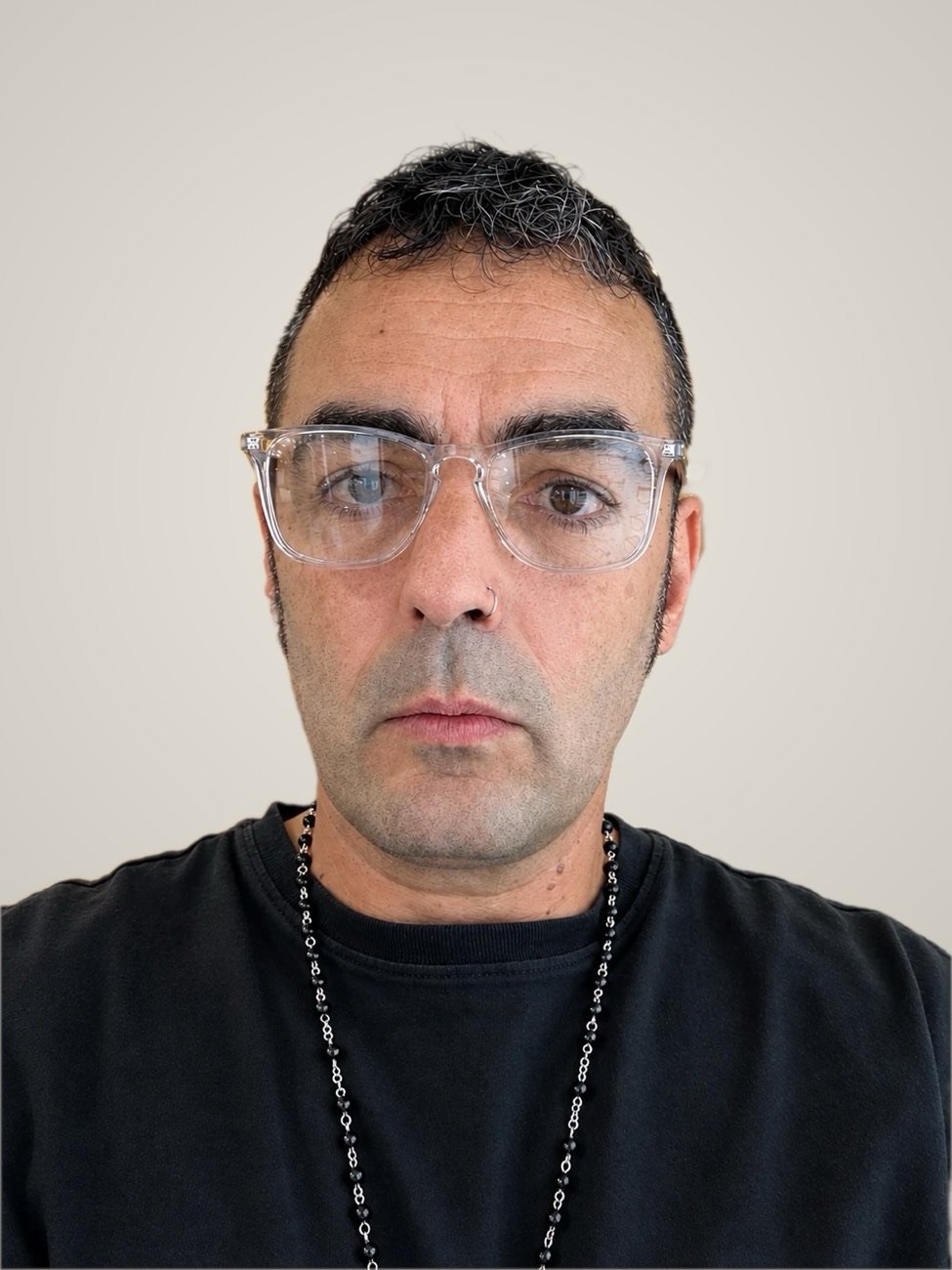 Carlos Barón Llinares hoy: gafas transparentes, camiseta negra y un rosario al cuello